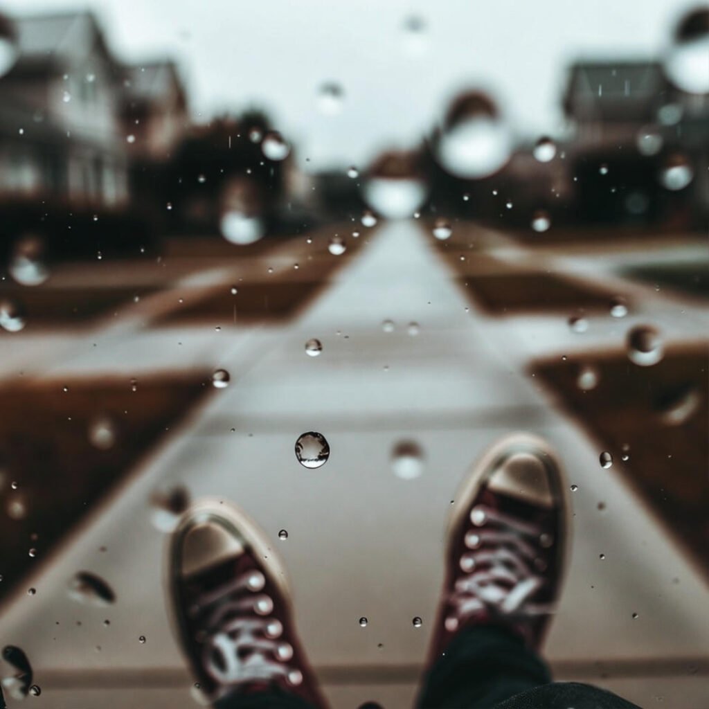 Wet sneakers walking rainy suburban sidewalk.