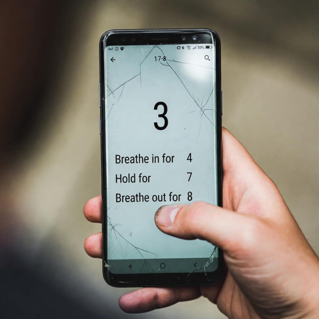 Hand holding cracked phone showing breathing timer.