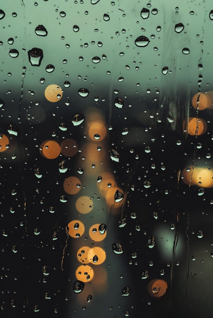 raindrops on a window with blurry city lights in the background—moody, cinematic, calming tones.