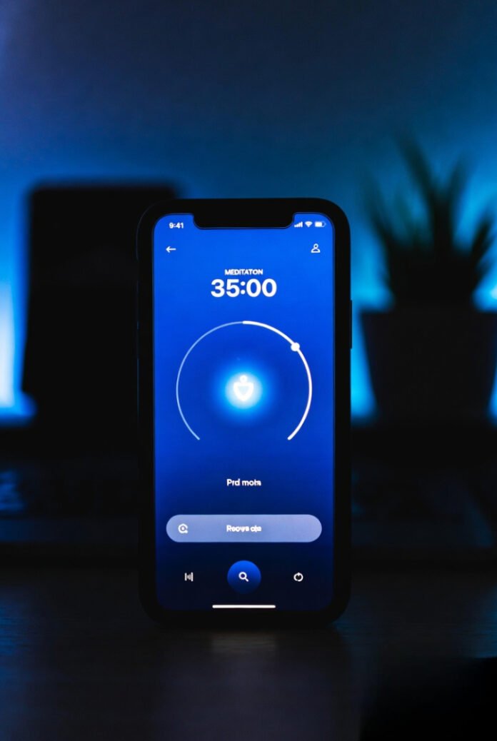 Close-up of a phone screen glowing in a dark room, meditation app open, soft shadows around.